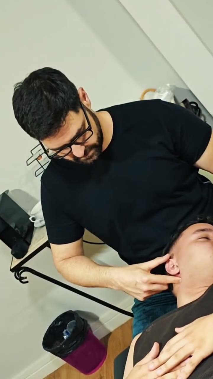 Fisioterapeuta avaliando a mandíbula de um paciente deitado na maca