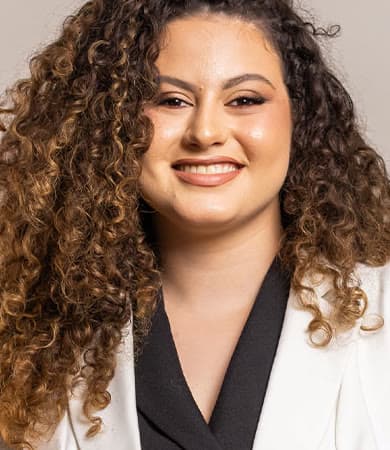 Retrato de Milena Aranha sorrindo, de blazer claro