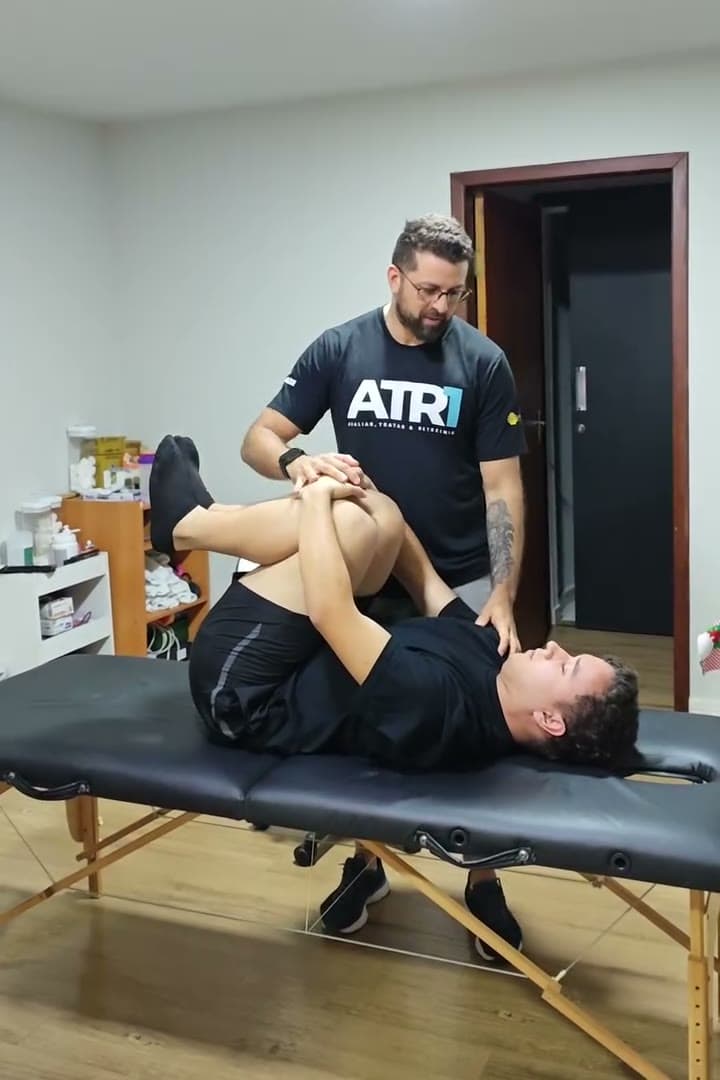 Professor Bruno Tavares demonstrando técnica de terapia manual em uma aluna deitada na maca, durante curso de fisioterapia na BioMoov em Maringá