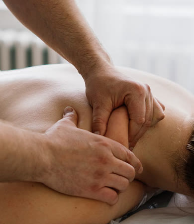 Mãos de fisioterapeuta fazendo liberação miofascial no ombro de um paciente